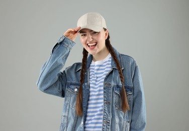 Photo of Happy woman in stylish baseball hat on grey background