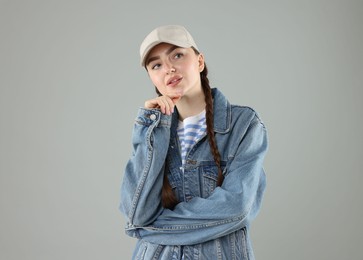 Photo of Thoughtful woman in stylish baseball hat on grey background