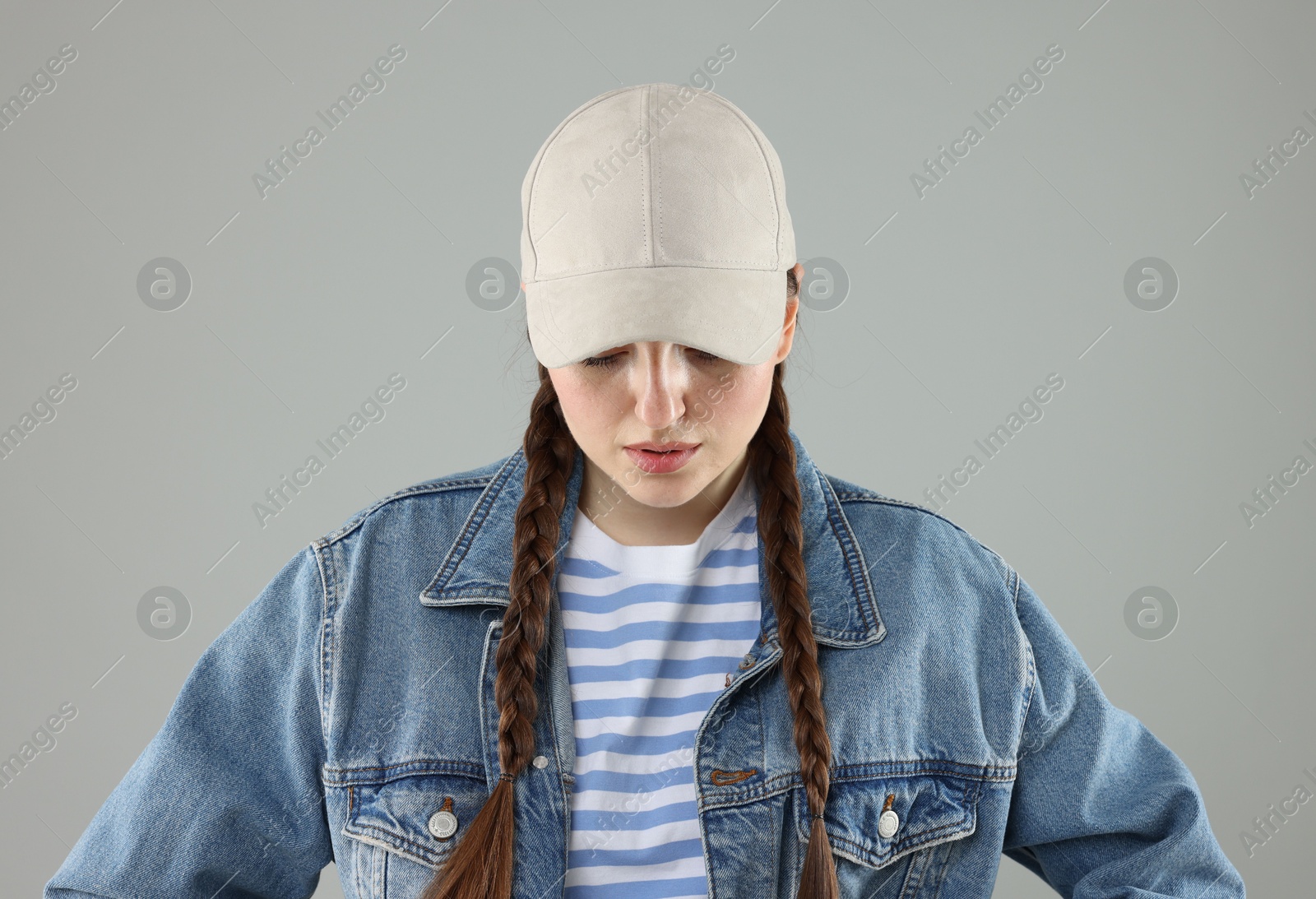 Woman in stylish baseball hat on grey background Photo of Woman in stylish baseball hat on grey background