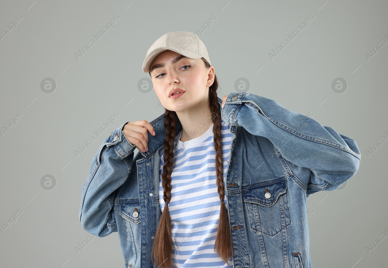 Beautiful woman in stylish baseball hat on grey background Photo of Beautiful woman in stylish baseball hat on grey background