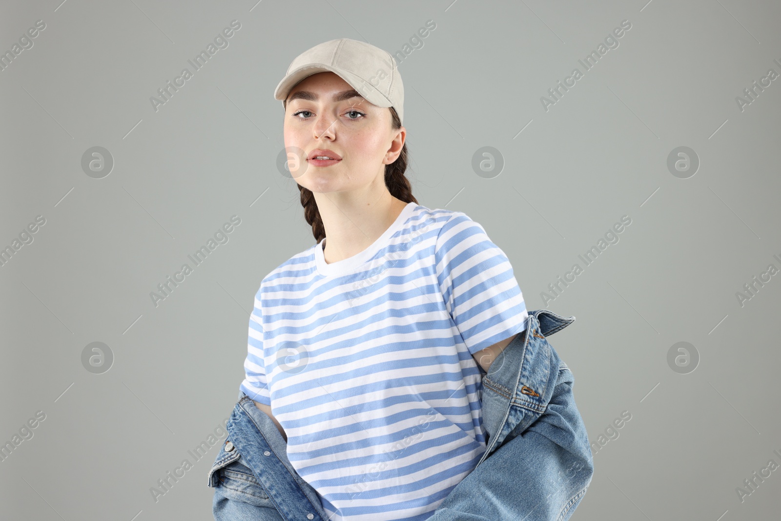 Portrait of beautiful woman in stylish baseball hat on grey background Photo of Portrait of beautiful woman in stylish baseball hat on grey background
