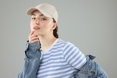 Photo of Portrait of beautiful woman in stylish baseball hat on grey background