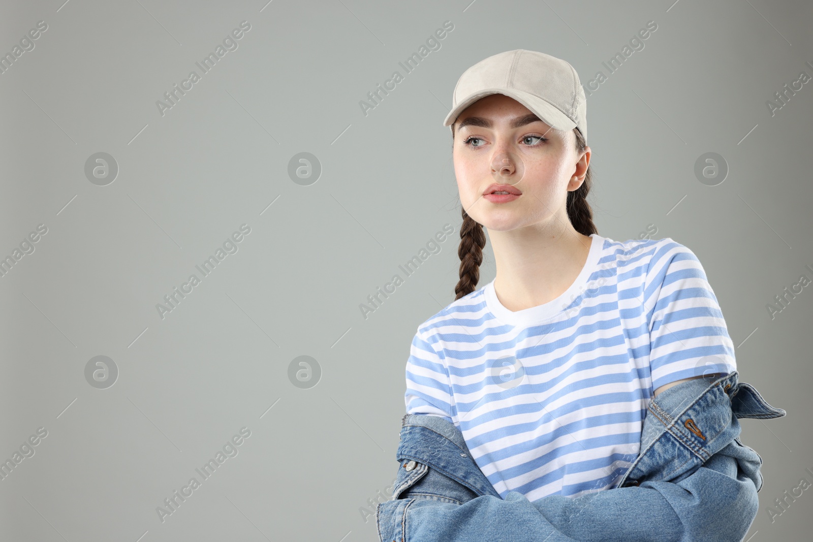 Beautiful woman in stylish baseball hat on grey background. Space for text Photo of Beautiful woman in stylish baseball hat on grey background. Space for text