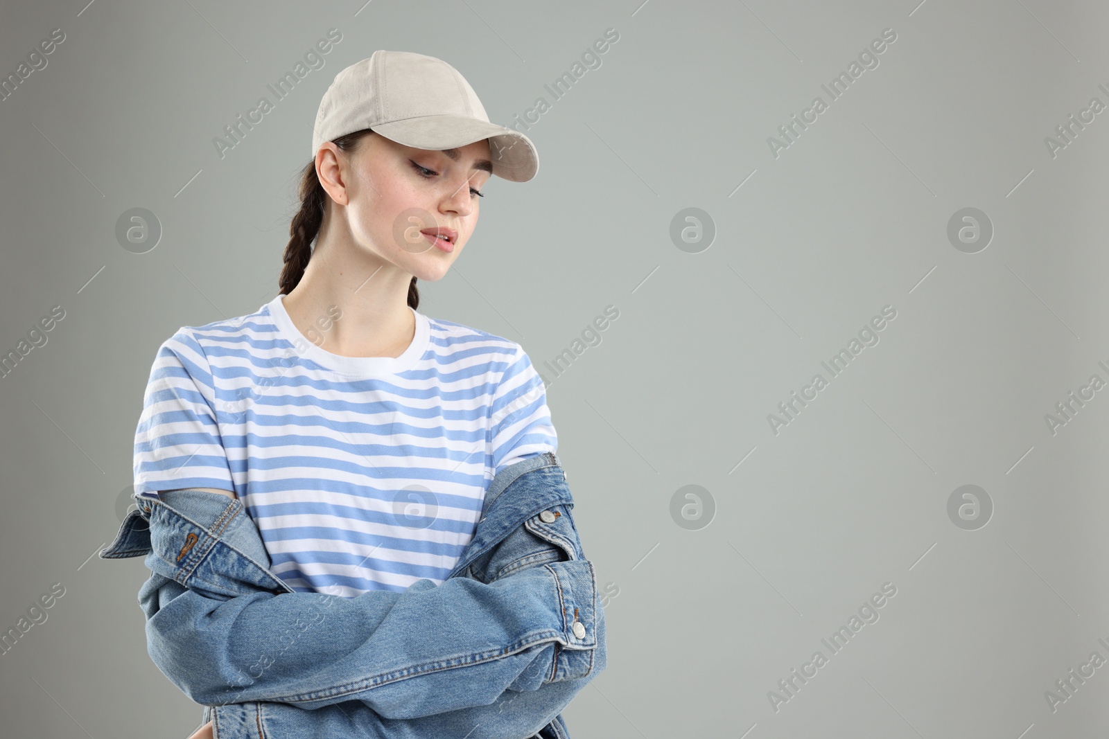Beautiful woman in stylish baseball hat on grey background. Space for text Photo of Beautiful woman in stylish baseball hat on grey background. Space for text