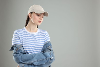 Photo of Beautiful woman in stylish baseball hat on grey background. Space for text