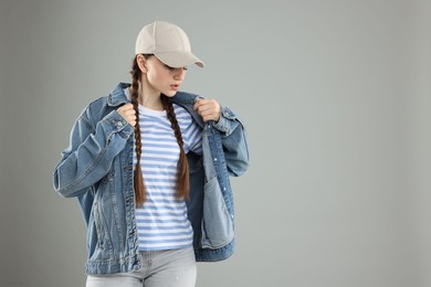 Photo of Beautiful woman in stylish baseball hat on grey background. Space for text