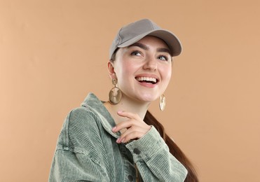Photo of Happy woman in stylish baseball hat on beige background