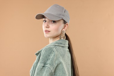 Photo of Portrait of beautiful woman in stylish baseball hat on beige background