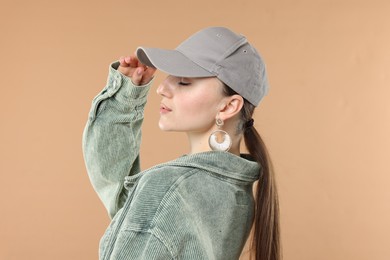 Photo of Beautiful woman in stylish baseball hat on beige background