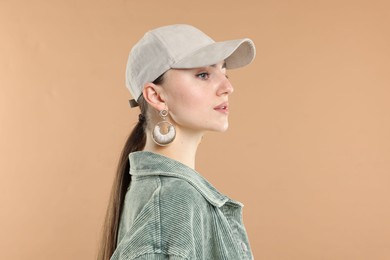 Photo of Beautiful woman in stylish baseball hat on beige background