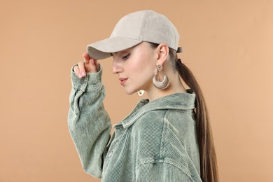 Photo of Beautiful woman in stylish baseball hat on beige background