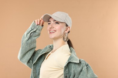 Photo of Smiling woman in stylish baseball hat on beige background