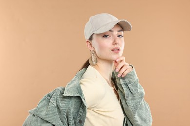 Photo of Portrait of beautiful woman in stylish baseball hat on beige background
