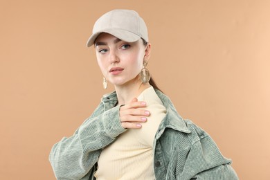 Photo of Portrait of beautiful woman in stylish baseball hat on beige background