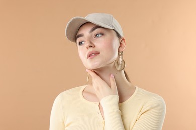 Photo of Beautiful woman in stylish baseball hat on beige background