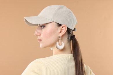 Photo of Beautiful woman in stylish baseball hat on beige background