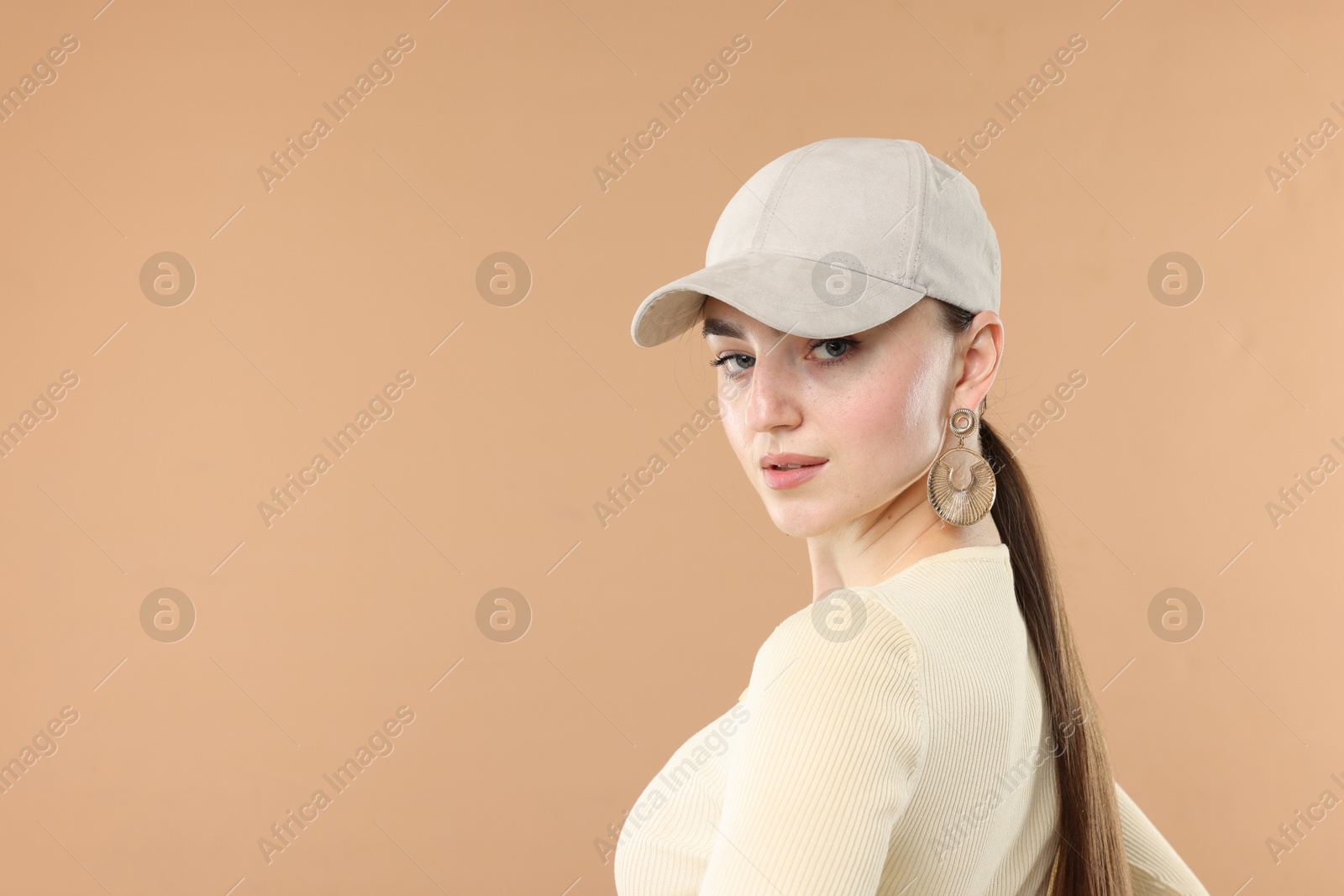 Beautiful woman in stylish baseball hat on beige background. Space for text Photo of Beautiful woman in stylish baseball hat on beige background. Space for text