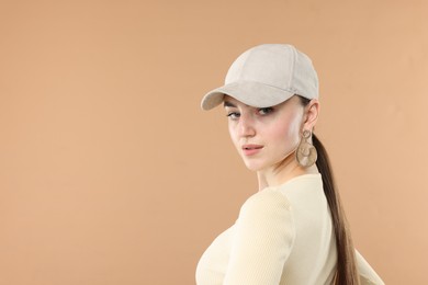 Photo of Beautiful woman in stylish baseball hat on beige background. Space for text
