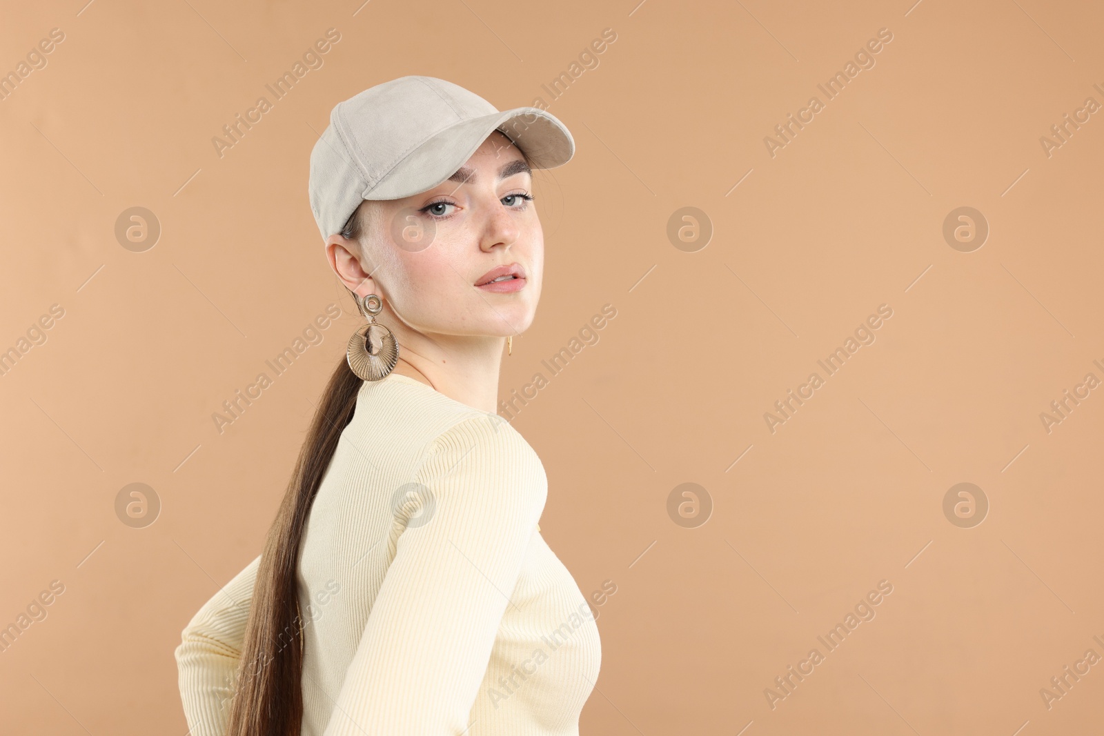 Beautiful woman in stylish baseball hat on beige background. Space for text Photo of Beautiful woman in stylish baseball hat on beige background. Space for text