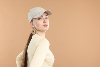 Photo of Beautiful woman in stylish baseball hat on beige background. Space for text