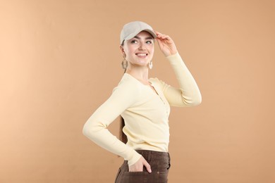 Photo of Smiling woman in stylish baseball hat on beige background