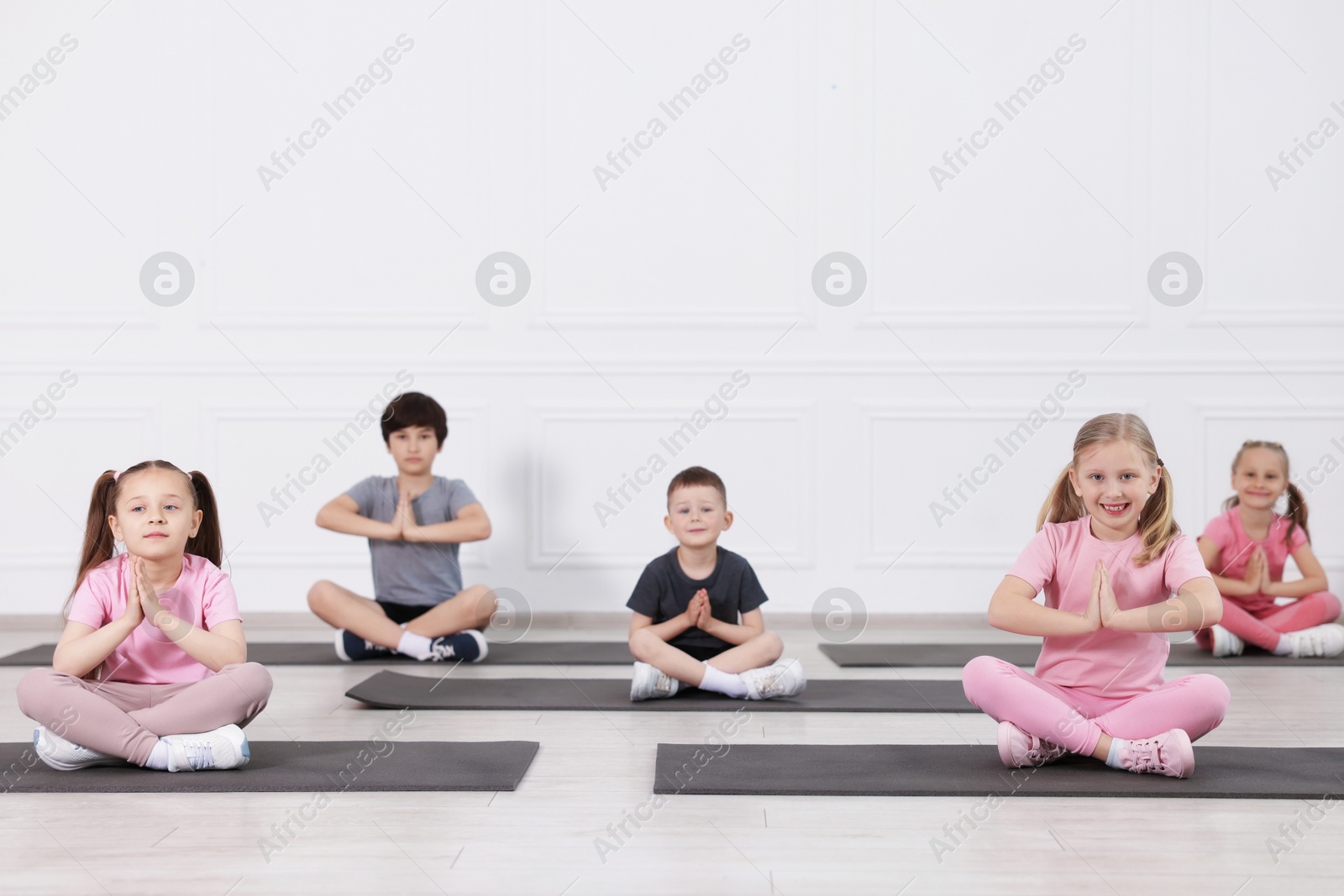 Group of children practicing yoga on mats in class Photo of Group of children practicing yoga on mats in class