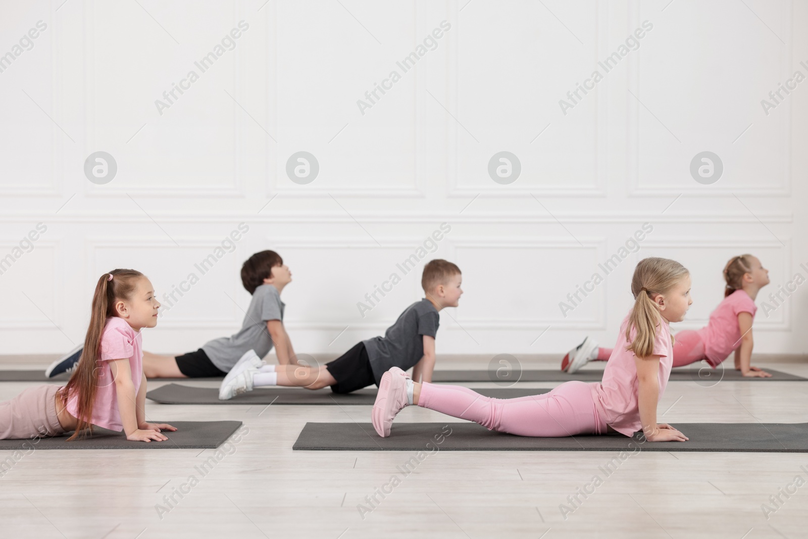 Group of children practicing yoga on mats in class Photo of Group of children practicing yoga on mats in class