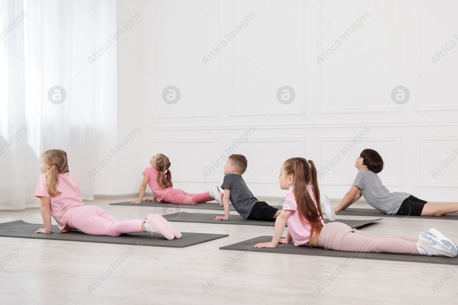 Group of children practicing yoga on mats in class Photo of Group of children practicing yoga on mats in class