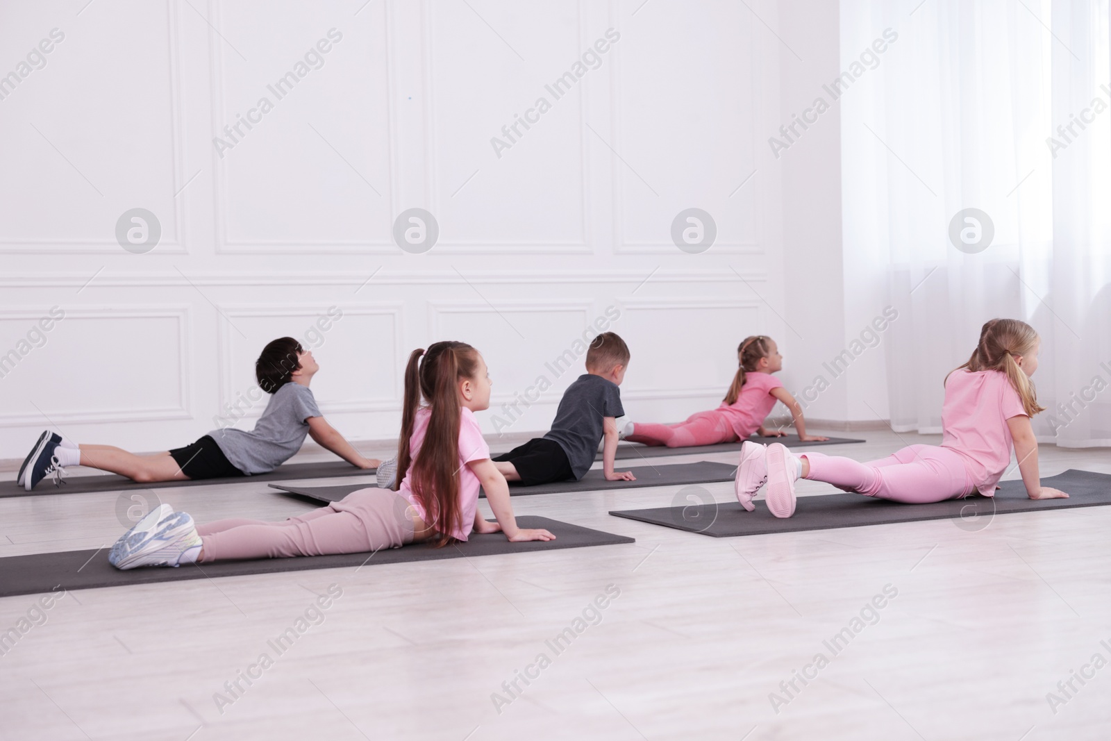 Group of children practicing yoga on mats in class Photo of Group of children practicing yoga on mats in class