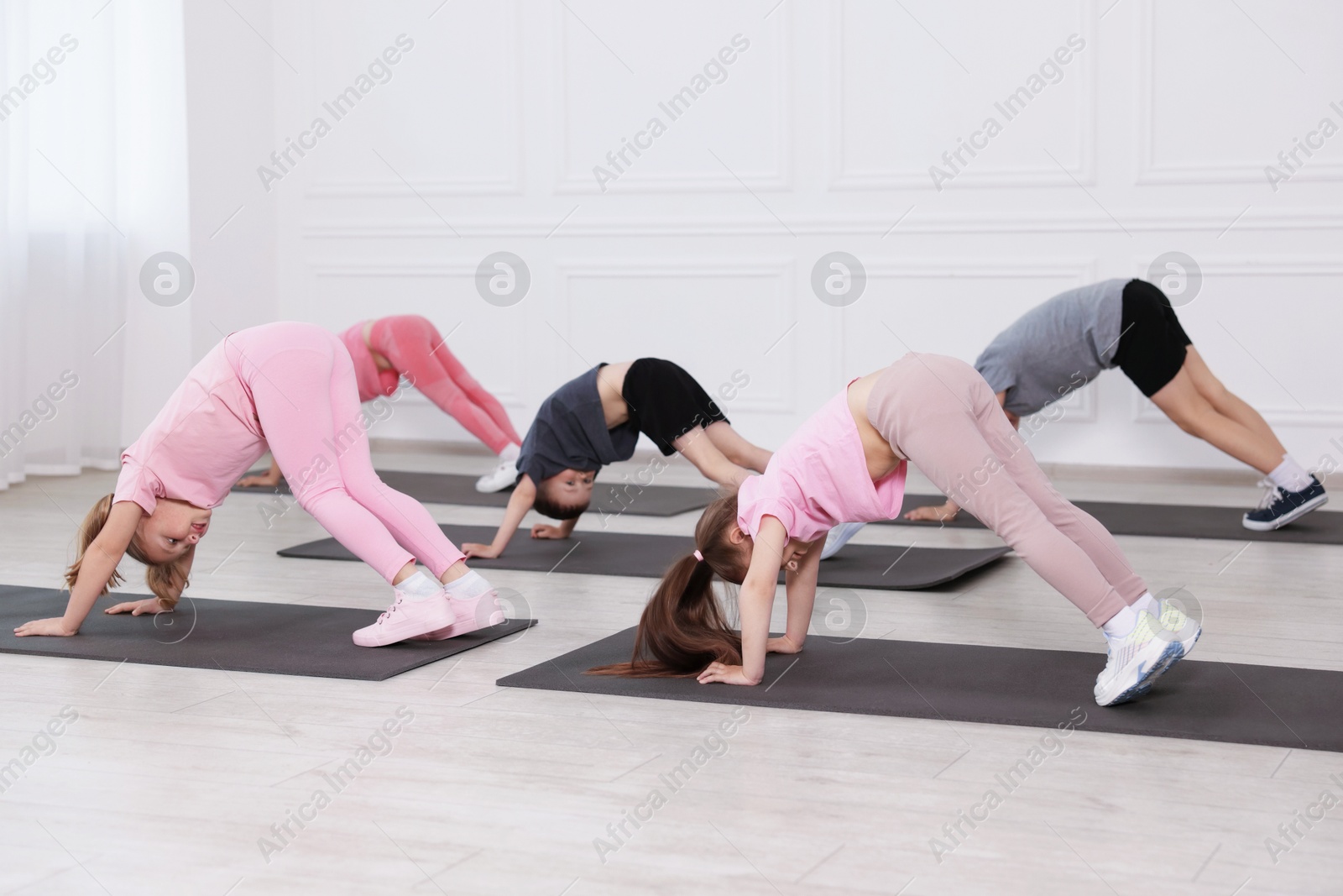 Group of children practicing yoga on mats in class Photo of Group of children practicing yoga on mats in class