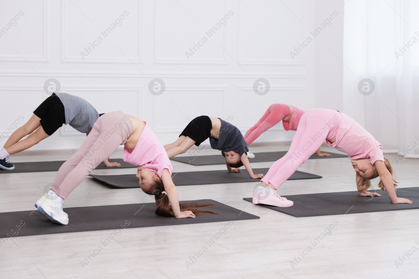 Group of children practicing yoga on mats in class Photo of Group of children practicing yoga on mats in class