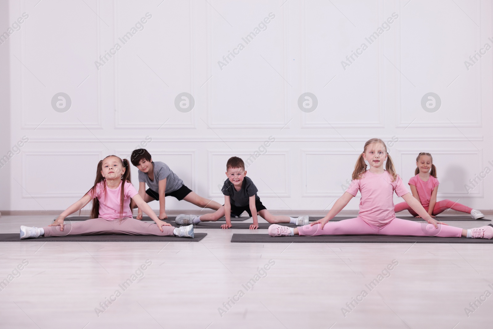 Group of children practicing yoga on mats in class Photo of Group of children practicing yoga on mats in class