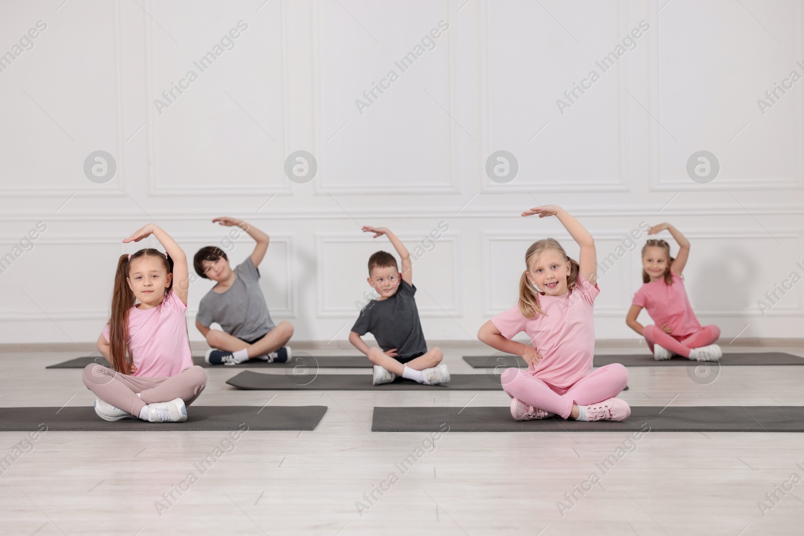 Group of children practicing yoga on mats in class Photo of Group of children practicing yoga on mats in class