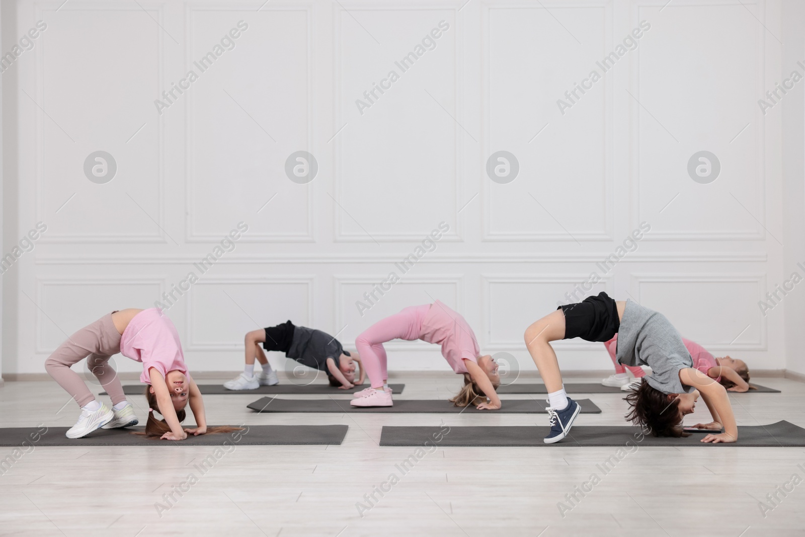 Group of children practicing yoga on mats in class Photo of Group of children practicing yoga on mats in class