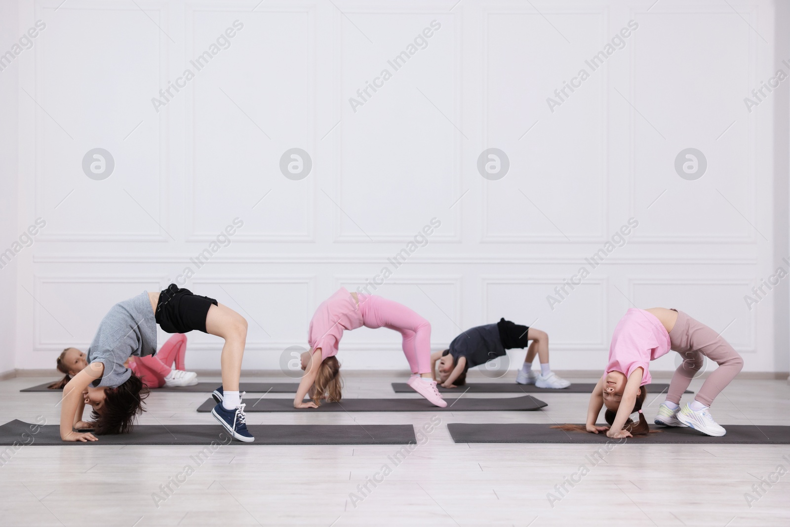 Group of children practicing yoga on mats in class Photo of Group of children practicing yoga on mats in class