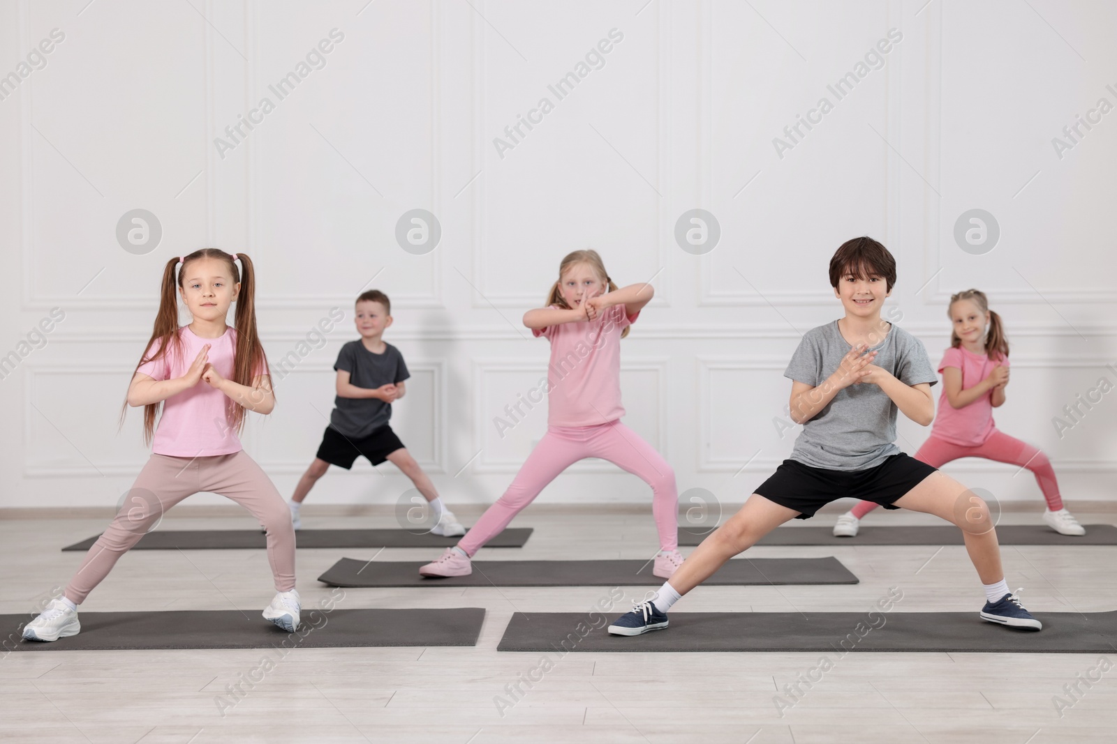 Group of children practicing yoga on mats in class Photo of Group of children practicing yoga on mats in class