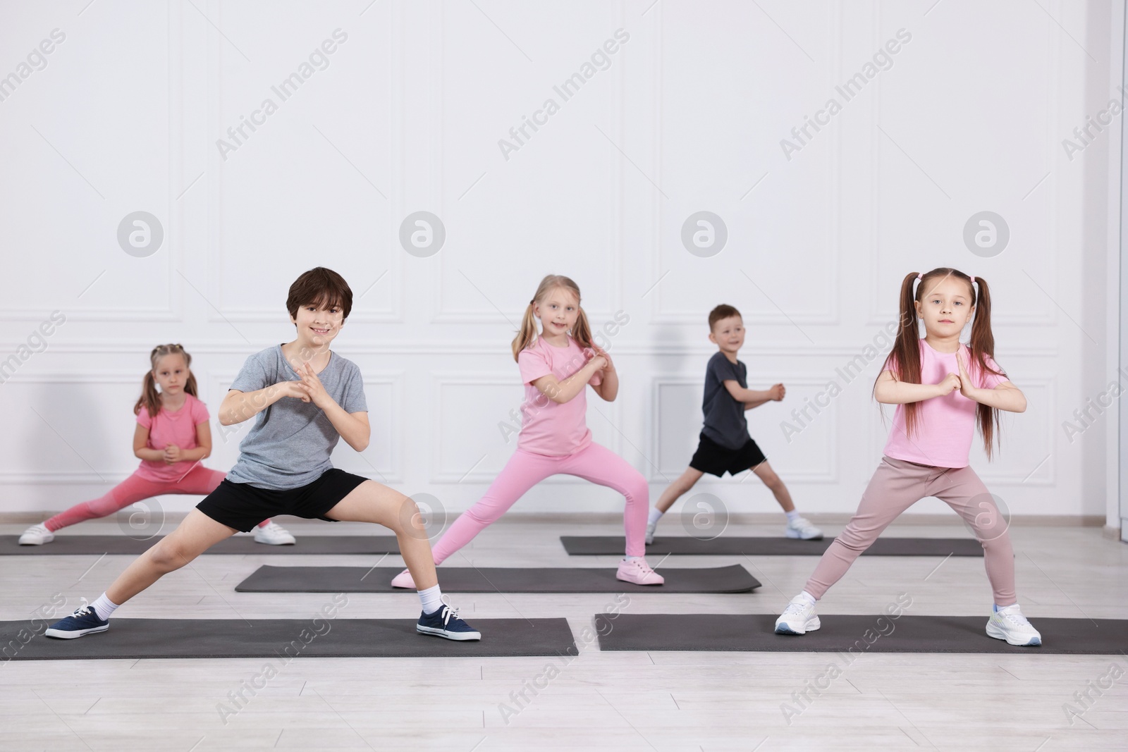 Group of children practicing yoga on mats in class Photo of Group of children practicing yoga on mats in class