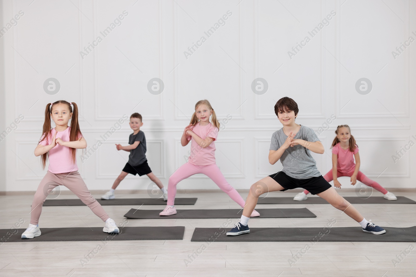 Group of children practicing yoga on mats in class Photo of Group of children practicing yoga on mats in class