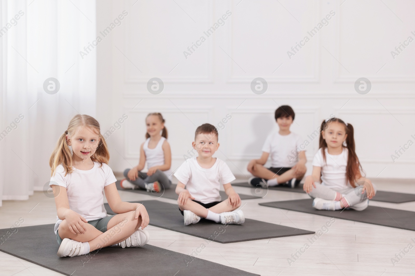 Group of children sitting on yoga mats in class Photo of Group of children sitting on yoga mats in class