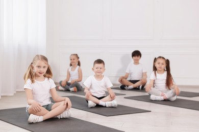 Photo of Group of children sitting on yoga mats in class