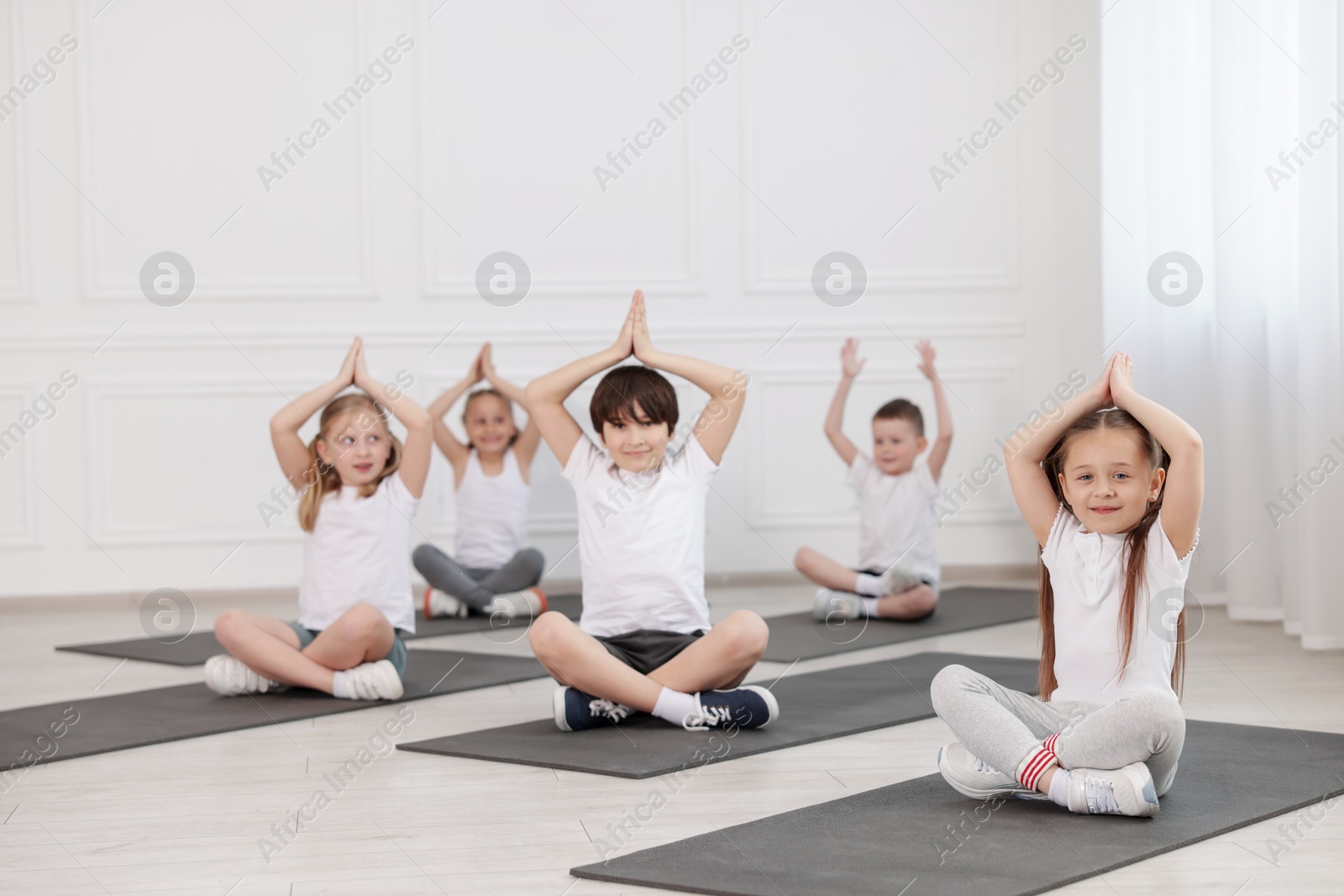 Group of children practicing yoga on mats in class Photo of Group of children practicing yoga on mats in class