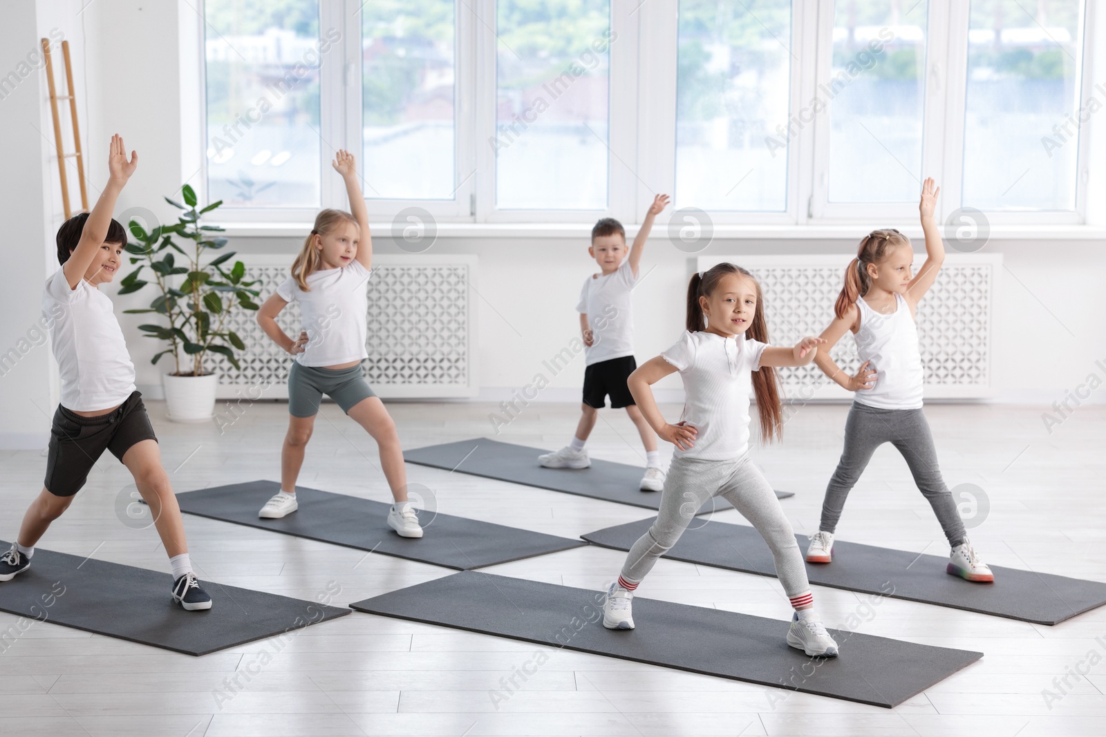 Group of children practicing yoga on mats in class Photo of Group of children practicing yoga on mats in class