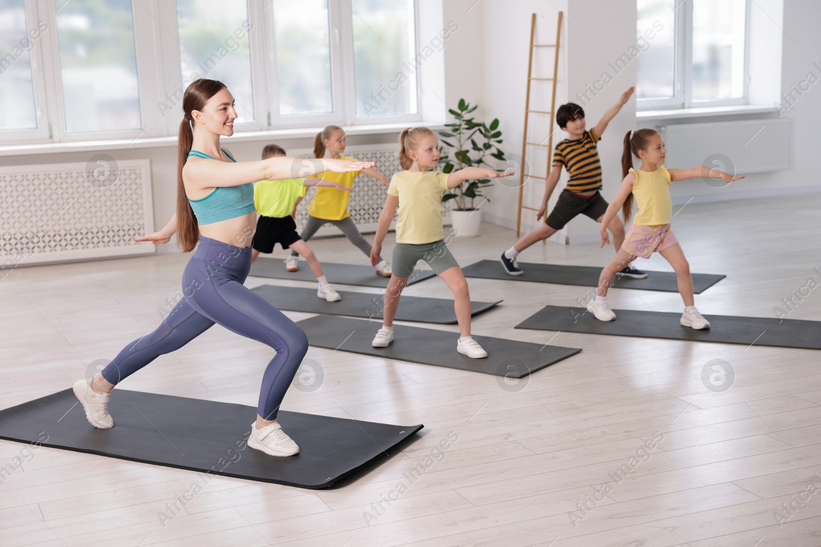 Group of children practicing yoga with coach on mats in class Photo of Group of children practicing yoga with coach on mats in class