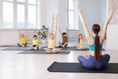 Photo of Group of children practicing yoga with coach on mats in class