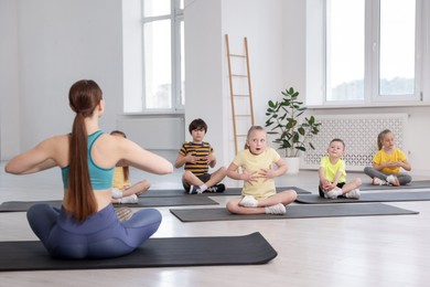 Photo of Group of children practicing yoga with coach on mats in class