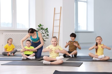 Photo of Yoga coach helping boy during group lesson indoors