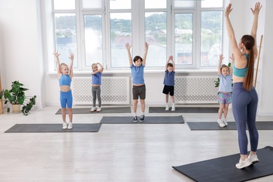 Photo of Group of children practicing yoga with coach on mats in class