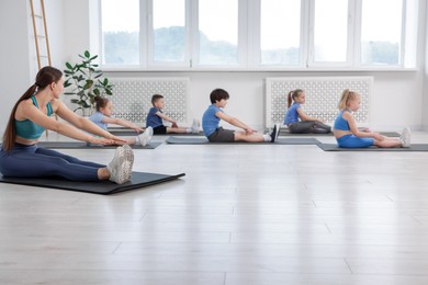 Photo of Group of children practicing yoga with coach on mats in class