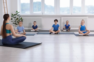 Photo of Group of children practicing yoga with coach on mats in class