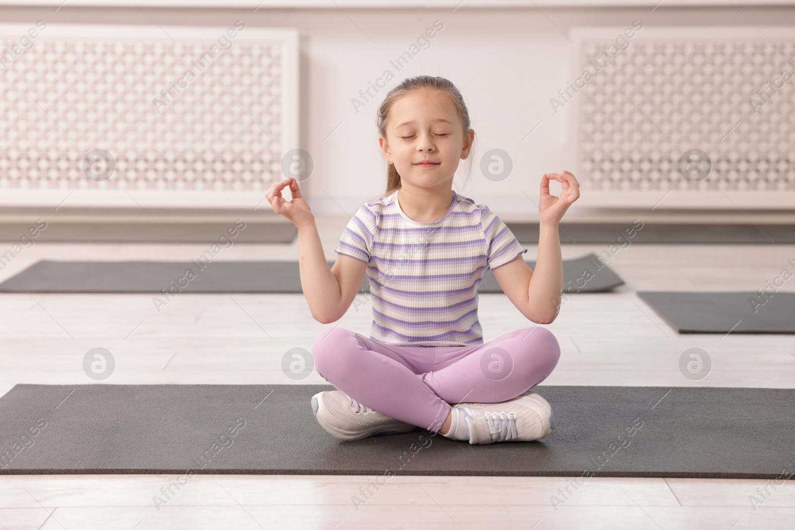 Cute girl meditating on yoga mat indoors Photo of Cute girl meditating on yoga mat indoors